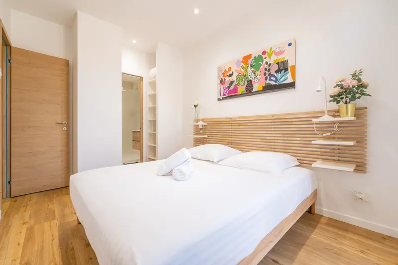 Chambre préparée avant une arrivée, linge hôtelier blanc et serviettes roulées sur le lit