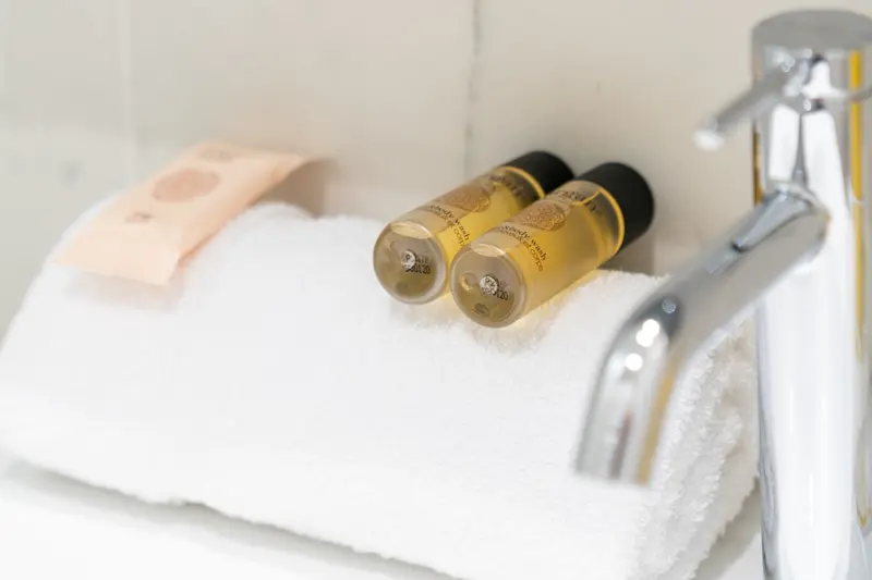 Produits d'accueil et serviette posés sur la vasque d'une salle de bain avant l'arrivée du voyageur