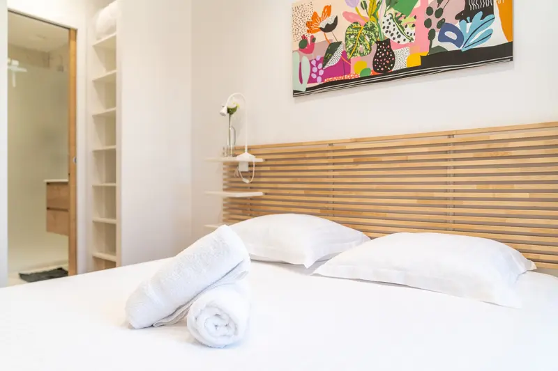 Serviettes roulées sur un lit fait, linge hôtelier fourni à chaque rotation